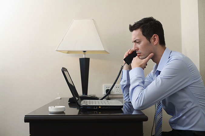 Businessman talking on the phone while using laptop